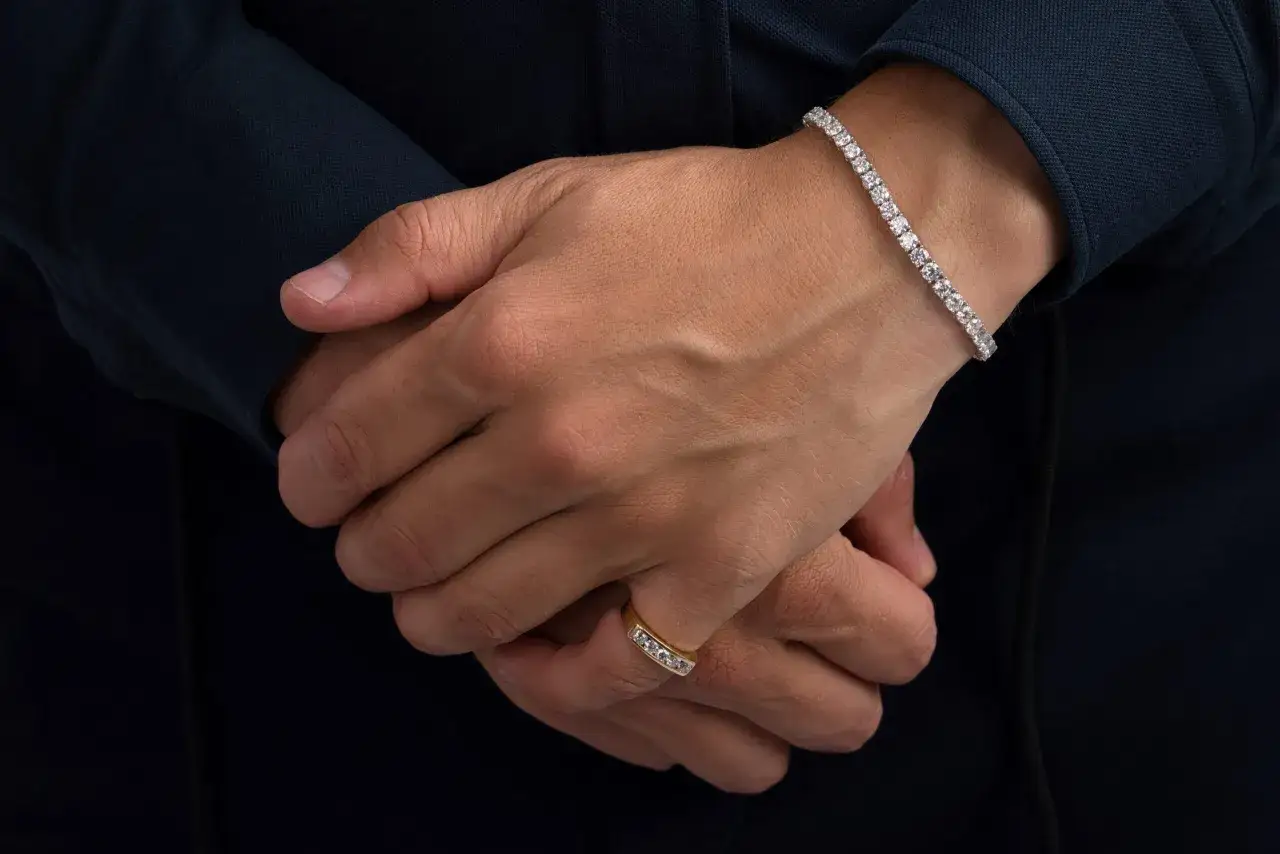 Mann tr&auml;gt elegantes Tennisarmband aus Gold mit Diamanten